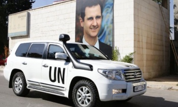 A poster of Syrian President Bashar al-Assad behind the vehicle of UN special envoy for Syria